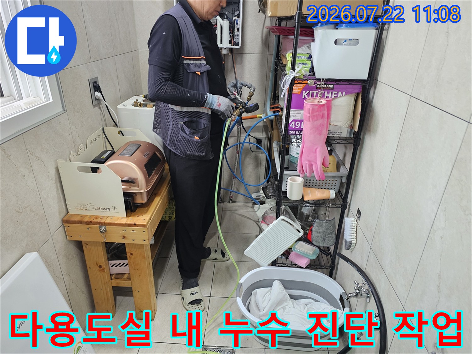 좁은 다용도실 공간에서 배관에 탐지 장비를 연결하고 점검하는 엔지니어