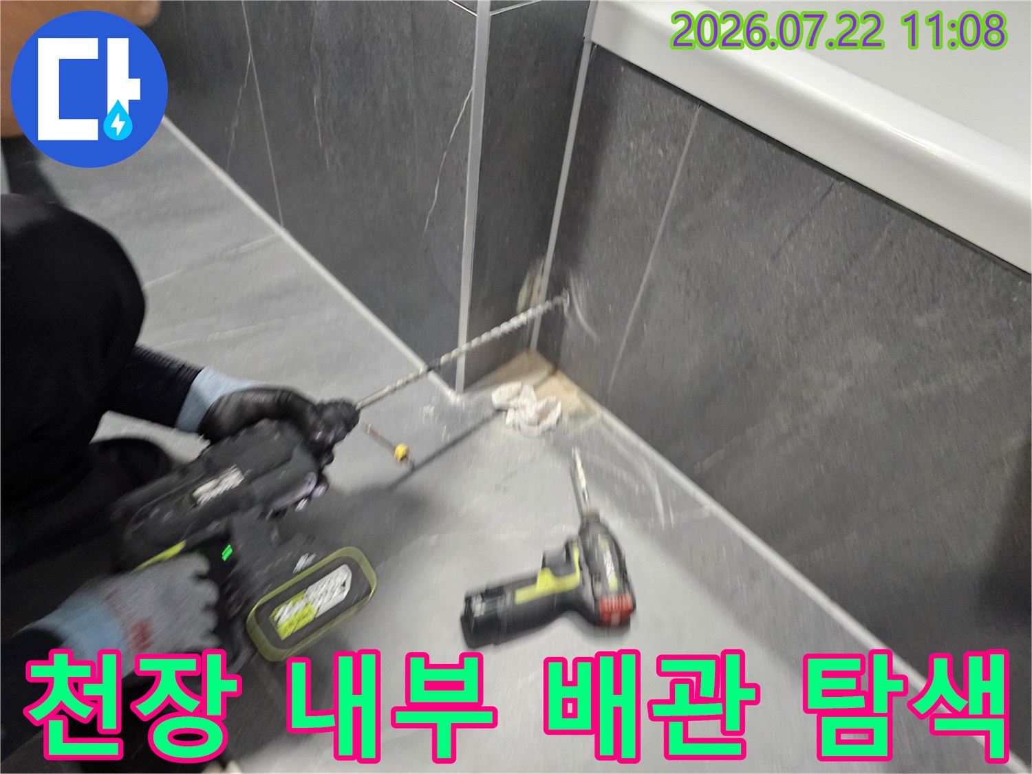 회색 콘크리트 천장에 전동 드릴을 사용하여 누수 지점을 파헤치는 작업 과정