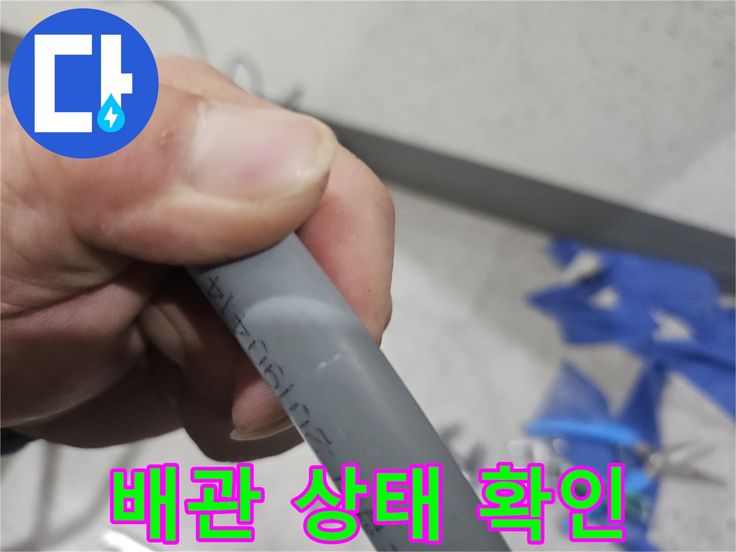 손으로 잡고 있는 회색 배관의 외관 점검