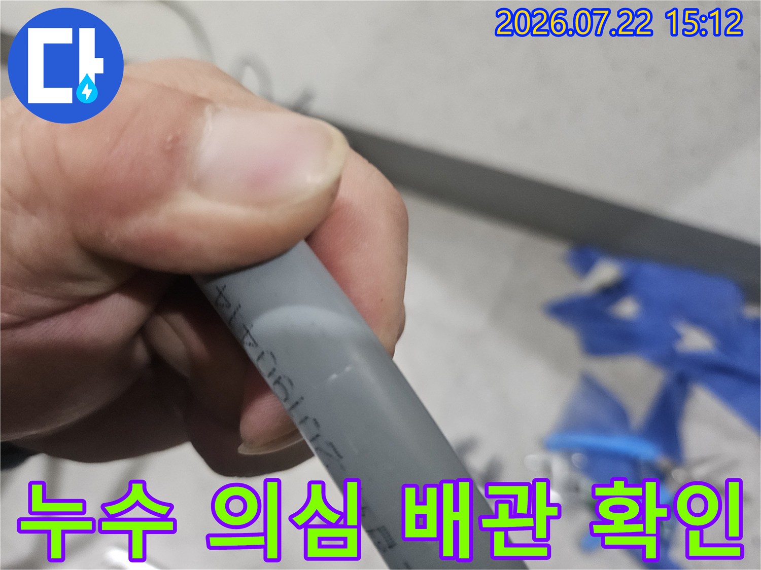 작업자가 손으로 회색 배관을 고정하고 표면의 마킹과 상태를 확인하는 모습-육안 검사