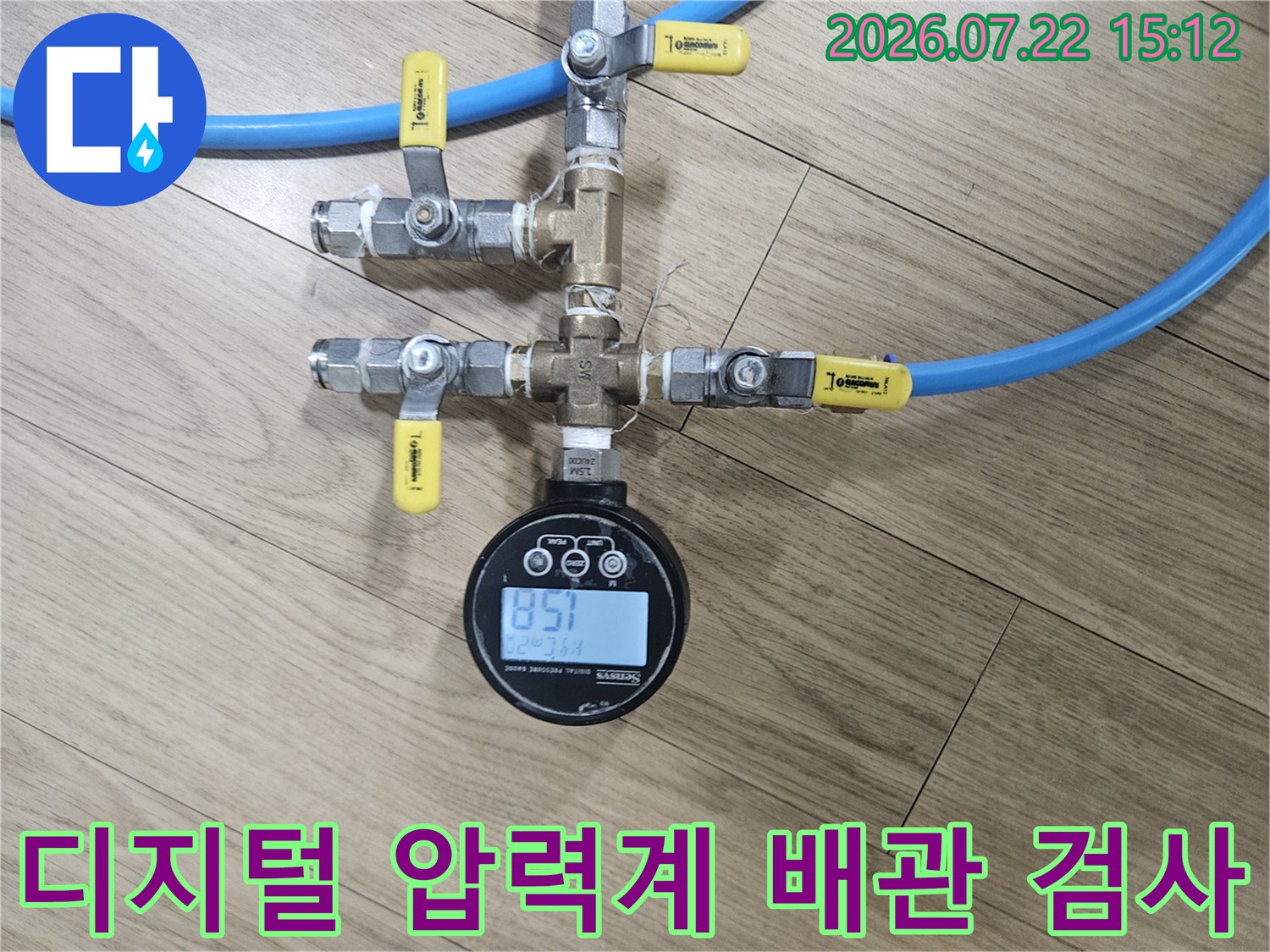파란색 호스와 연결된 금속 배관 위에 디지털 압력 측정기가 설치된 모습