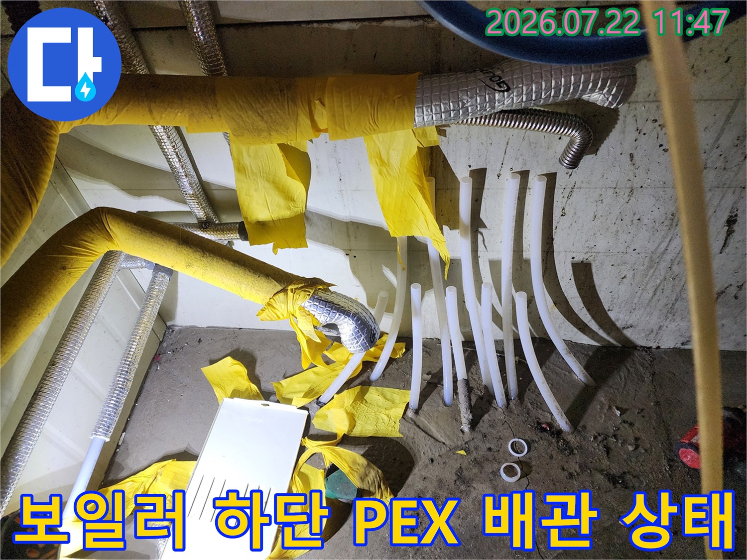 노란색 보온재로 감싸진 보일러 하단 배관과 흰색 PEX 분배기 라인-누수 점검 모습