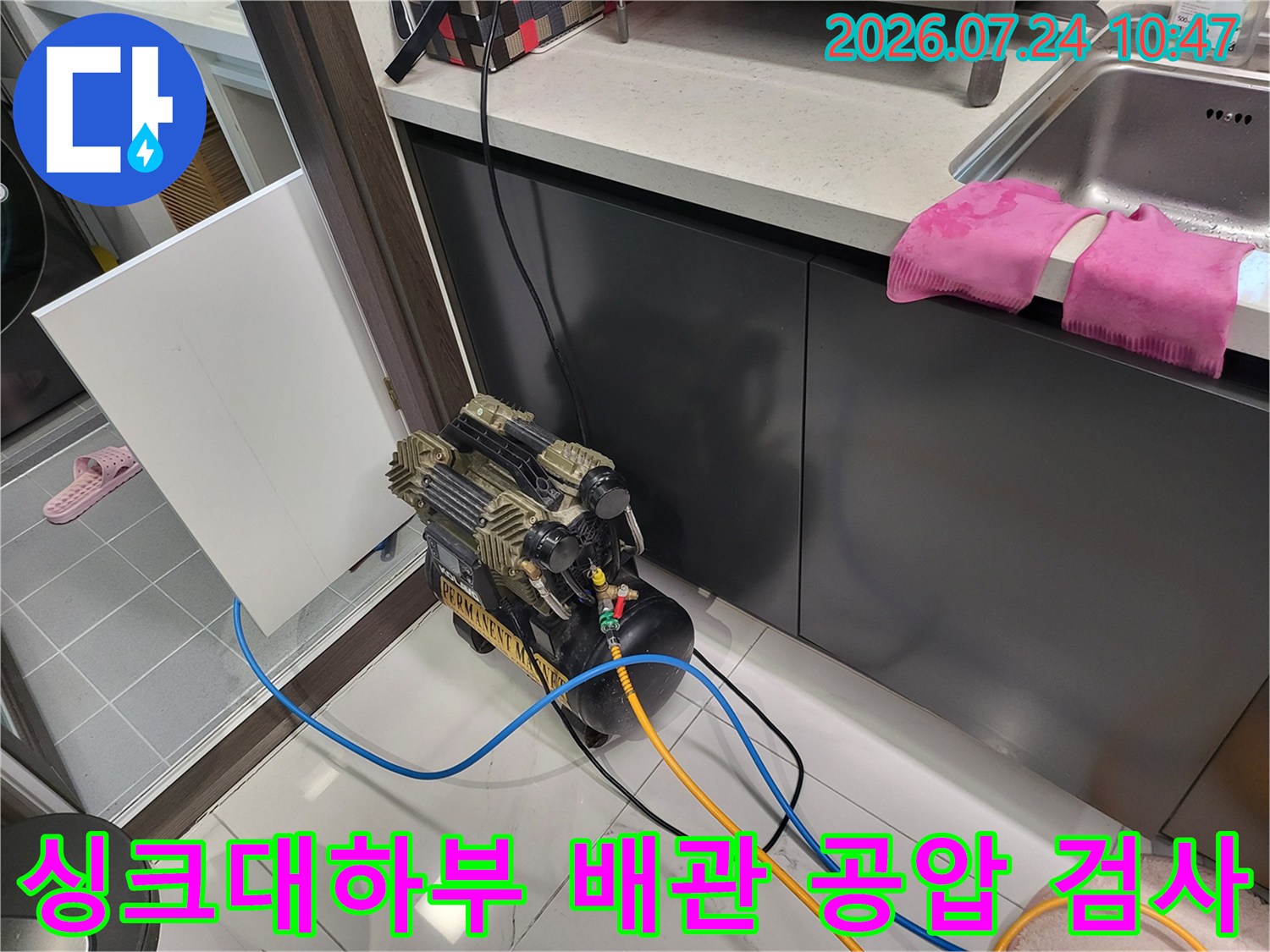 싱크대 아래쪽에서 배관에 압력 장비를 연결하여 누수 여부를 점검하는 모습
