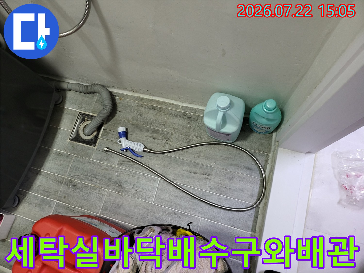 세탁실-바닥-배수구-주변에-놓인-청소용품과-보일러-연결-배관-사진