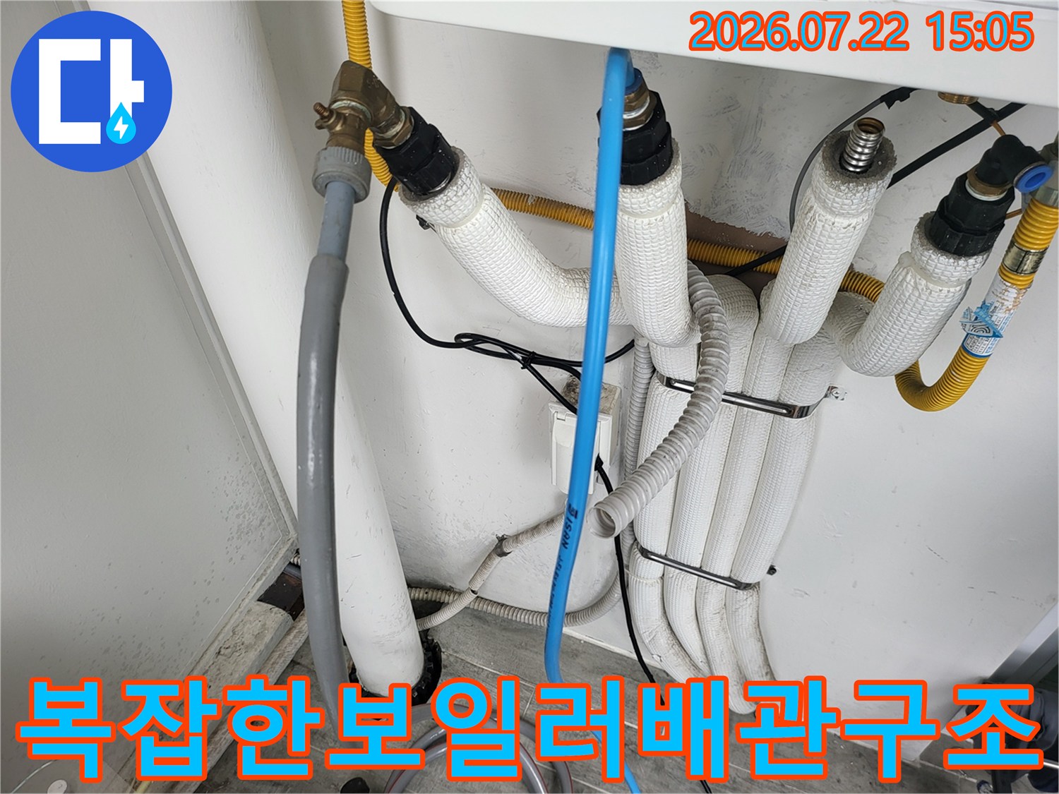 흰색 단열재가 입혀진 여러 개의 배관과 파란색 얇은 관이 나란히 배치된 모습