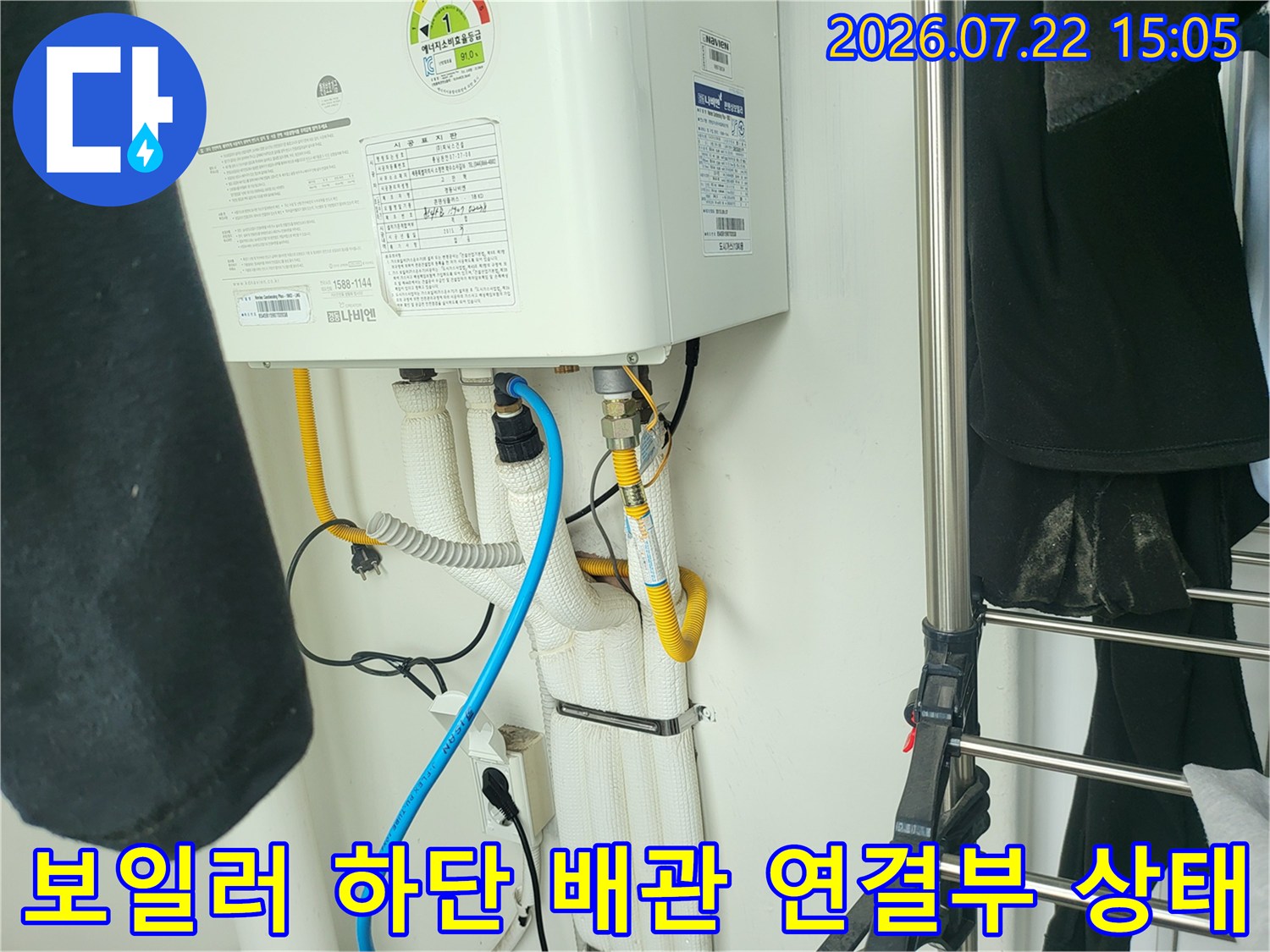 흰색 보온재로 감싸진 보일러 하단 배관과 파란색 호스가 연결된 모습