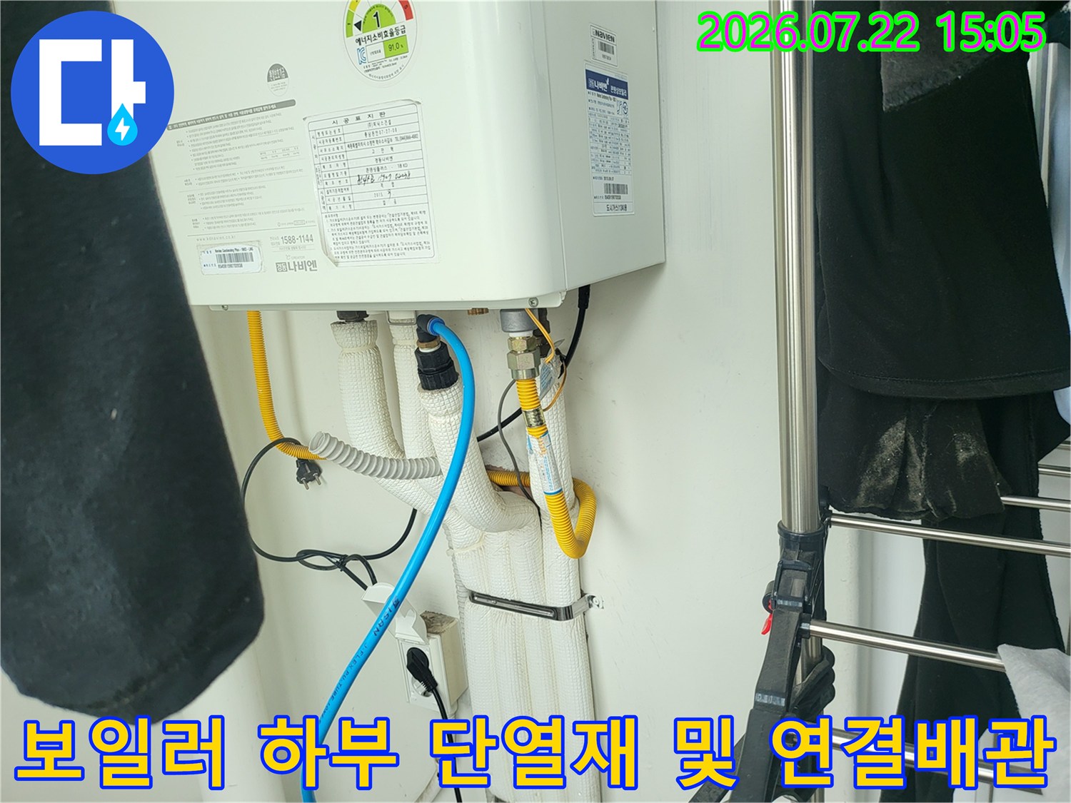 흰색 보온재로 덮인 보일러 배관과 파란색 플라스틱 호스가 연결된 상태