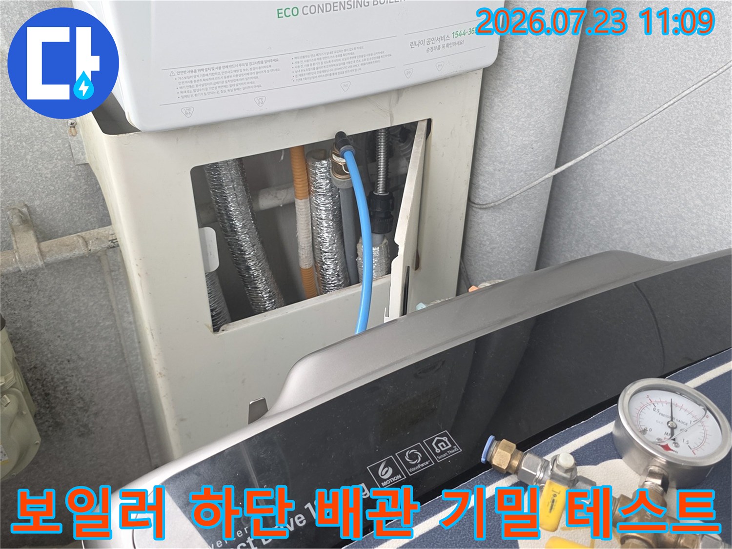 파란색 튜브와 압력 게이지가 연결된 보일러실 내부의 배관 설비 모습