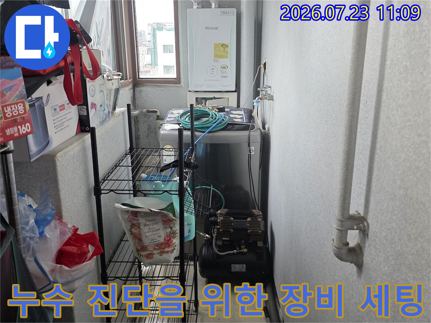 흰색 벽면의 보일러실 공간에 설치된 누수 탐지용 컴프레셔와 연결 배관-사진