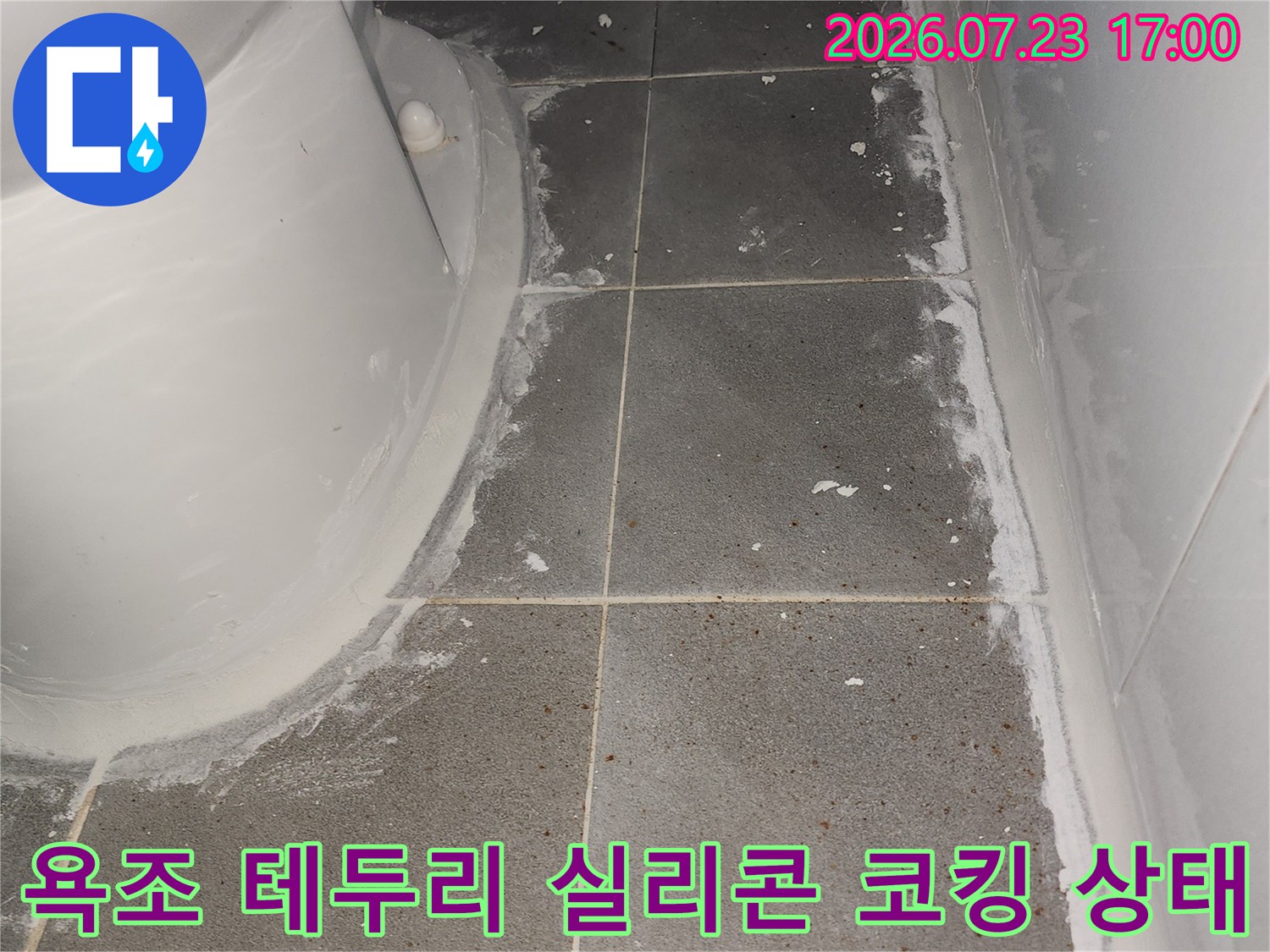 흰색 욕조의 상단 곡선 부위와 회색 타일 벽면이 실리콘으로 밀폐된 모습