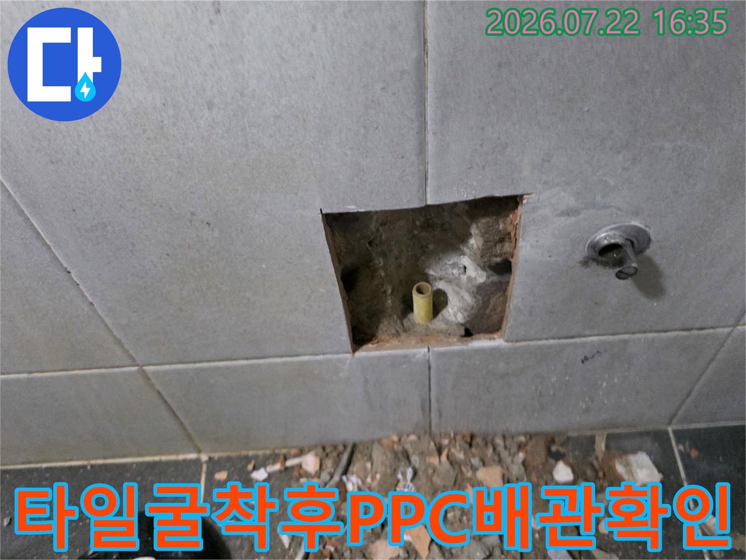 회색-타일-벽면의-사각형-절개부위-속에-노란색-수도배관이-돌출되어-있는-모습
