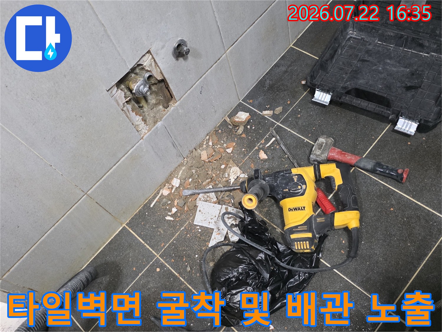 흰색 타일 벽면에 사각형 모양으로 구멍을 내어 내부의 매립 배관을 노출시킨 모습