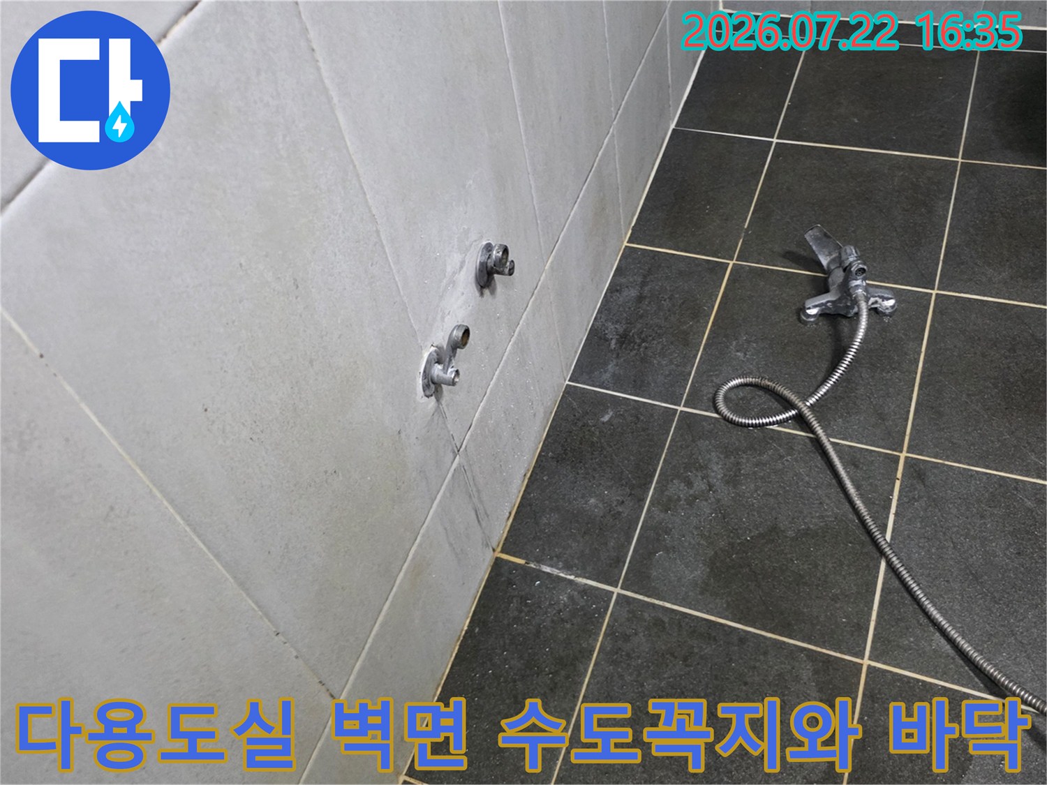 흰색 타일 벽면에 설치된 두 개의 수도 꼭지와 바닥에 놓인 샤워 호스-누수 점검 전 모습