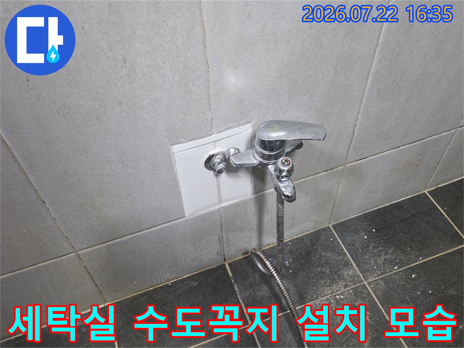 흰색 타일 벽면에 설치된 은색 금속제 수도꼭지와 연결된 호스-모습