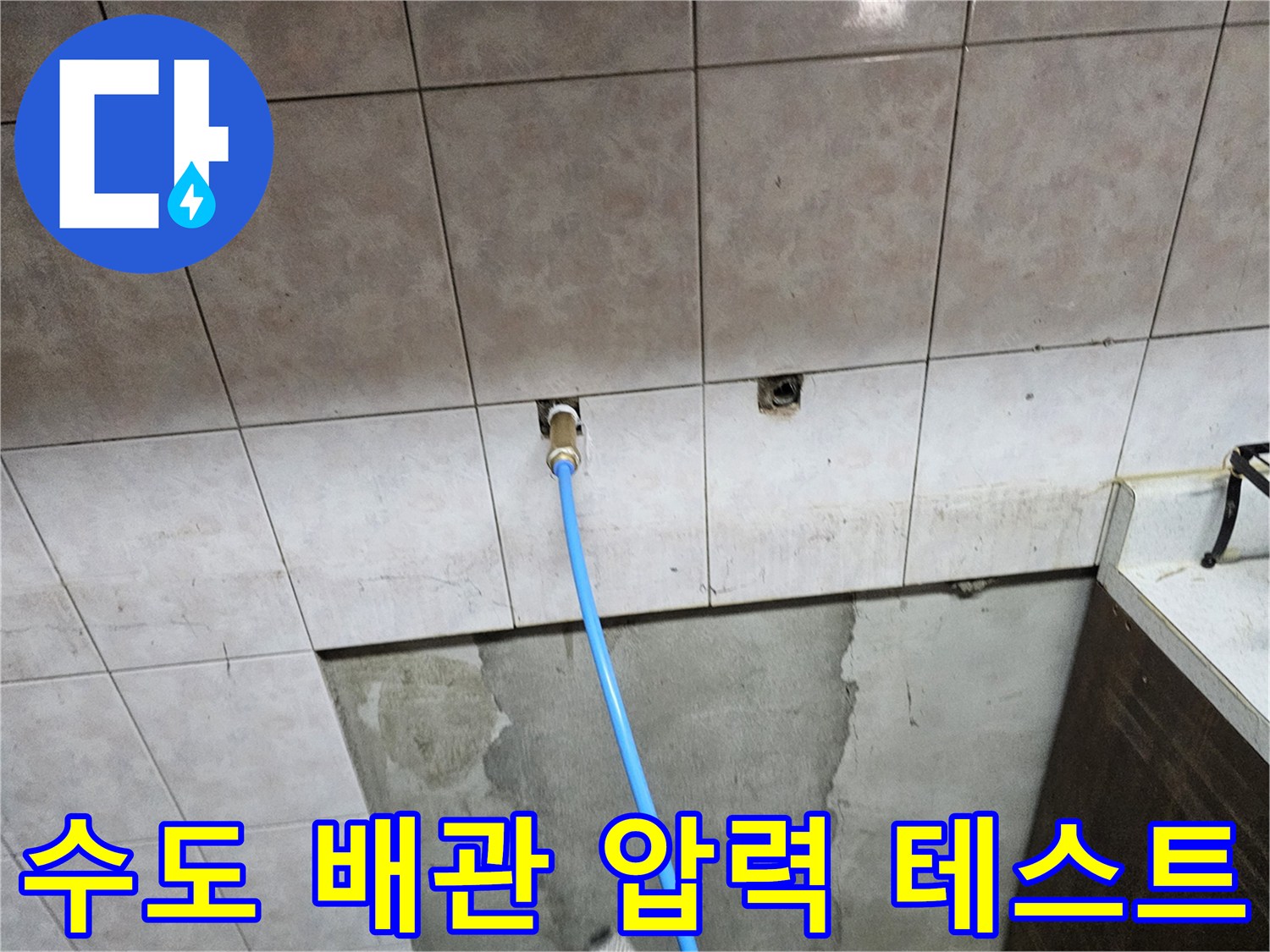 벽면 배관 연결구에 연결된 파란색 점검용 호스