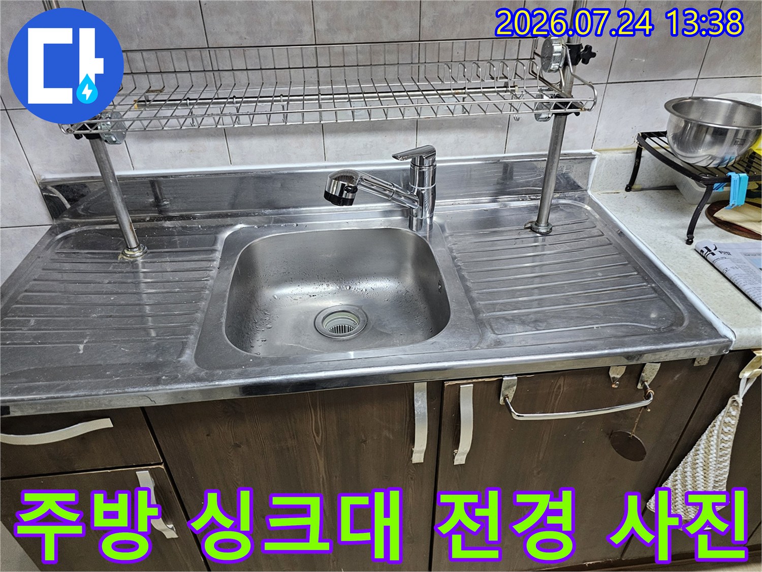 스테인리스 소재의 주방 싱크대와 상단 식기 건조대가 설치된 모습