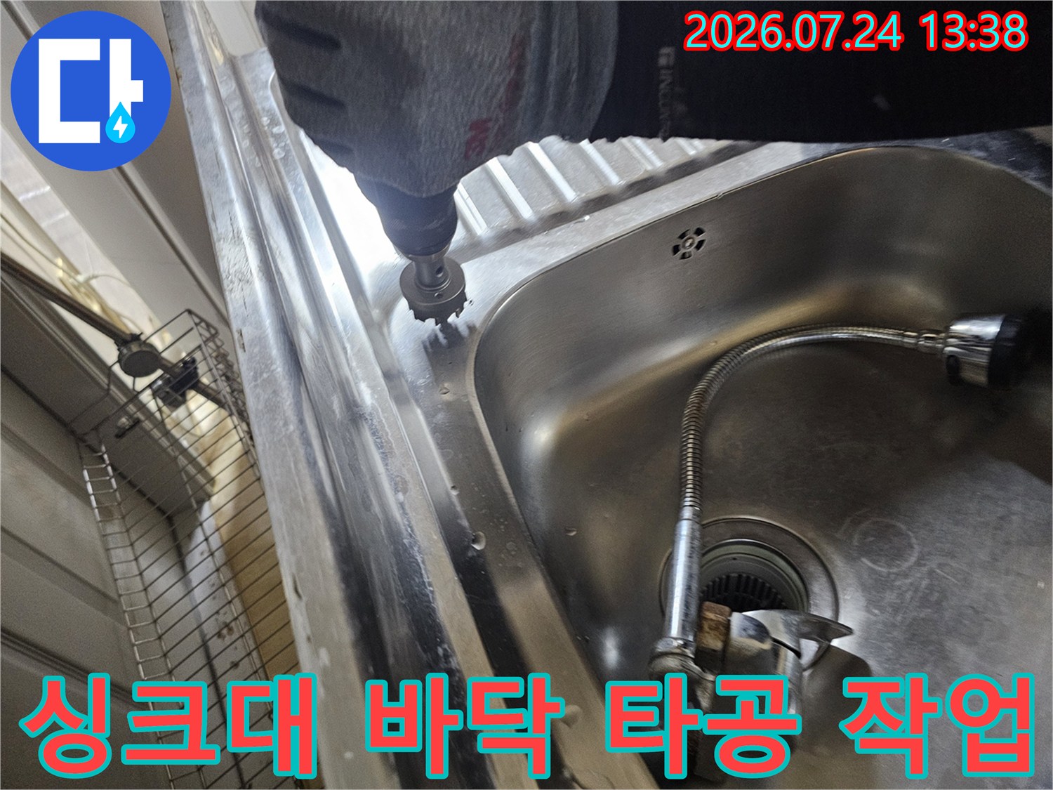 작업자가 전동 드릴을 사용하여 싱크대 하부 바닥면을 정밀하게 타공하는 모습