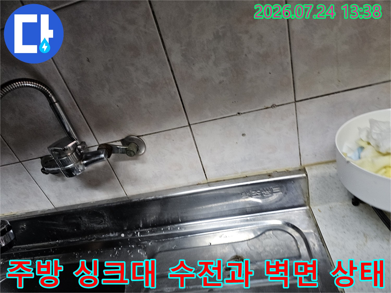 주방 싱크대의 스테인리스 상판과 은색 수전-그리고 타일 벽면의 모습