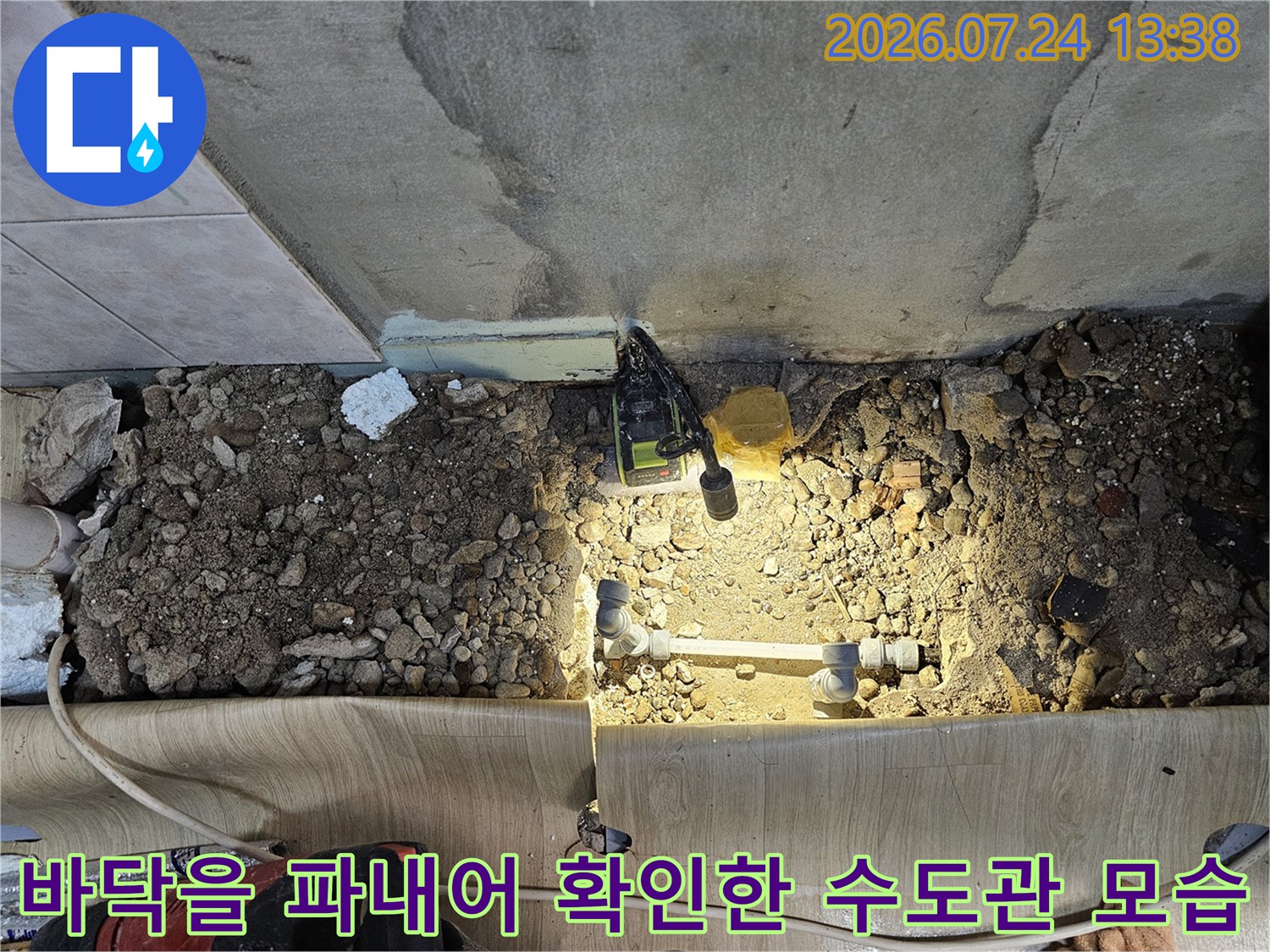 흙과 시멘트 잔해 속에 노출된 부식된 금속 배관-누수 지점 특정
