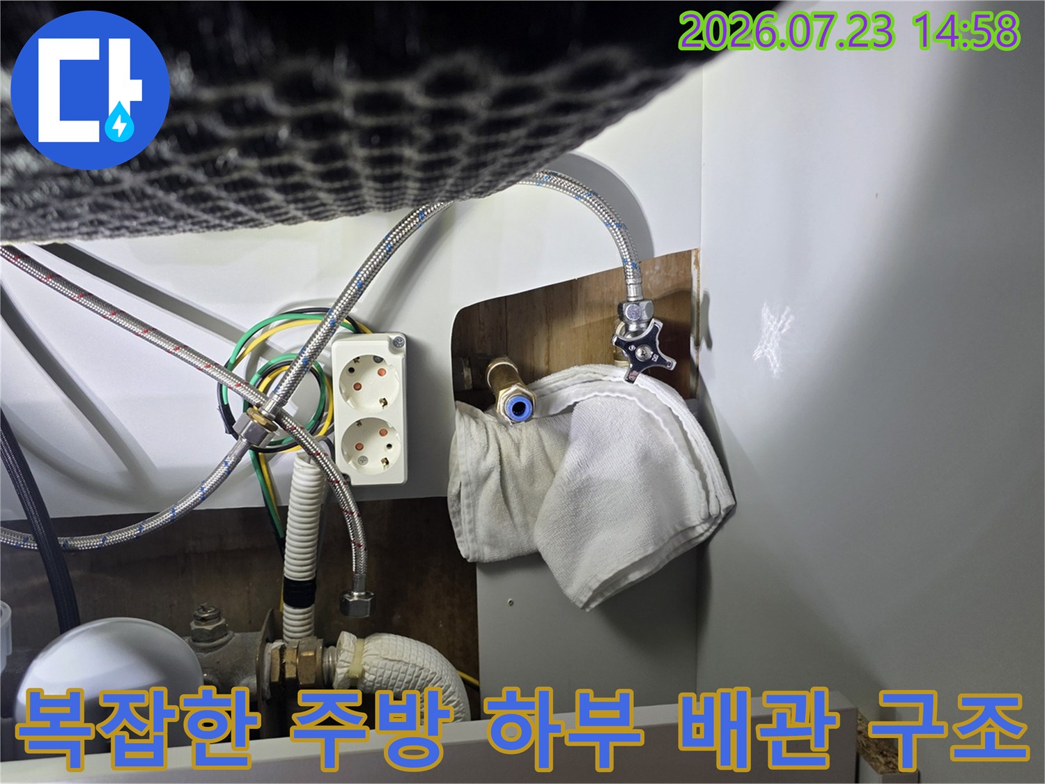 다양한 굵기의 급수 및 배수 호스가 얽혀 있는 싱크대 내부-와 전기 소켓의 배치