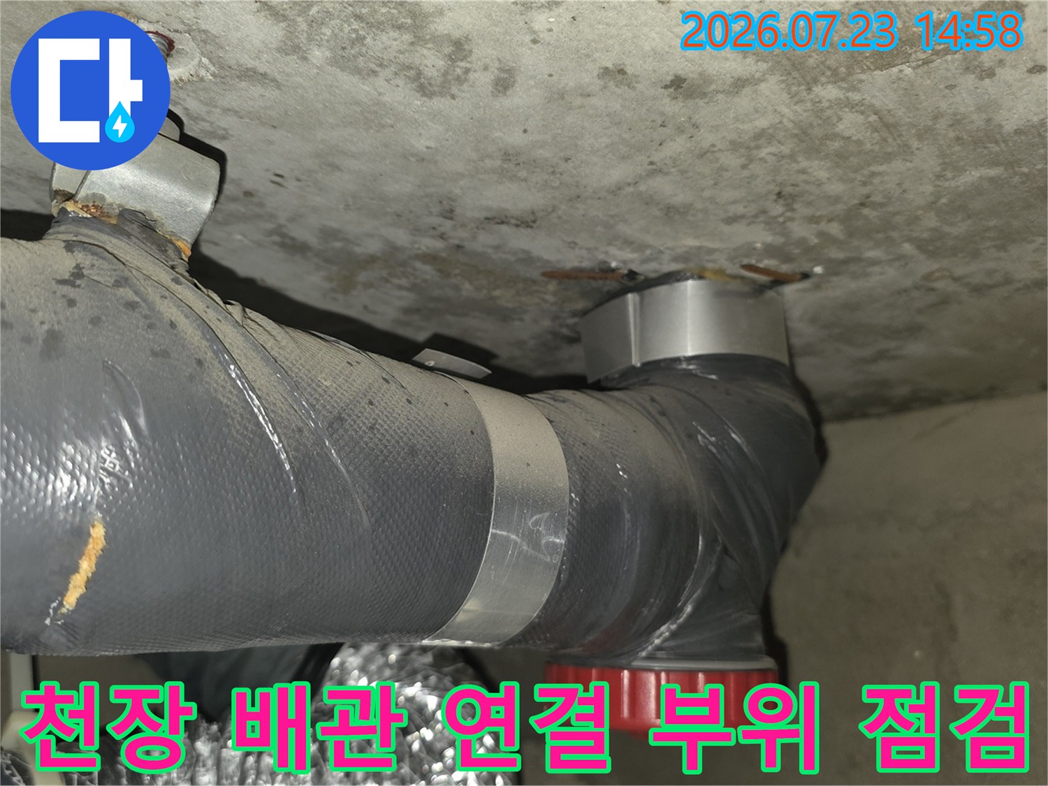 콘크리트 천장에 고정된 회색 배관과 빨간색 캡 연결 부위-누수 점검 모습