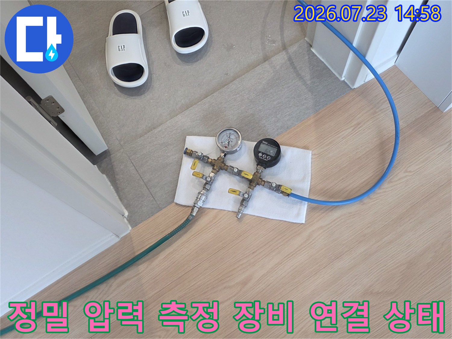 흰색 천 위에 배치된 누수 탐지용 공압 게이지와 파란색 및 초록색 호스-사진
