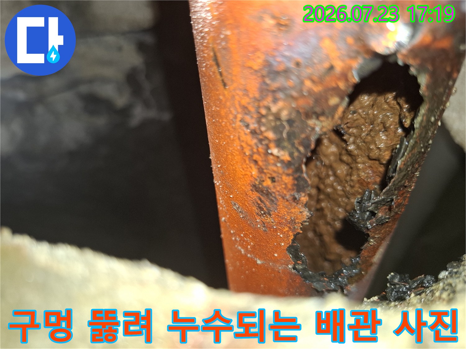 오렌지색 배관 외벽이 부식되어 커다란 구멍이 생긴 모습-누수 원인 지점