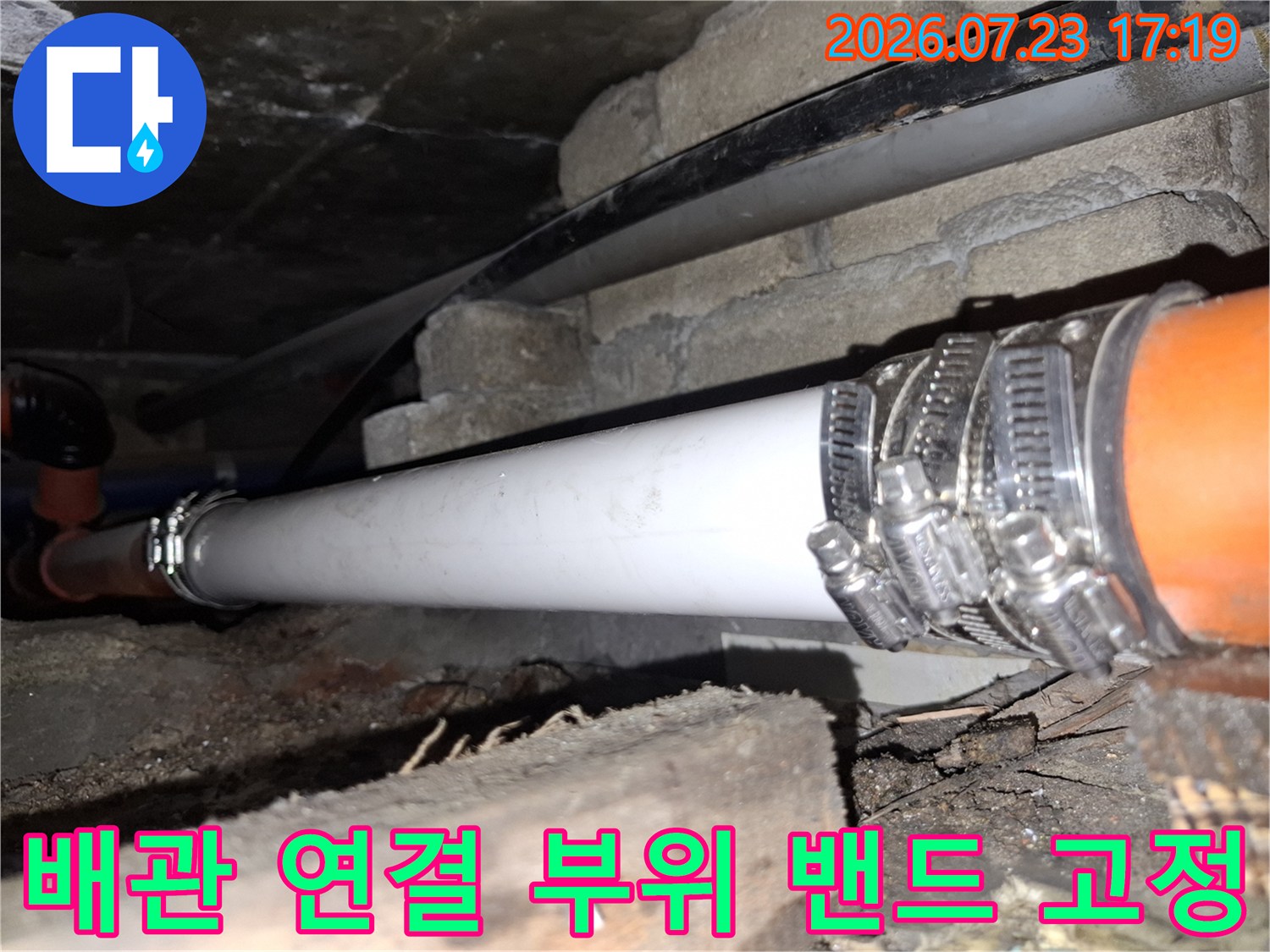 오렌지색 배관과 흰색 배관을 호스 밴드로 단단히 연결한 모습