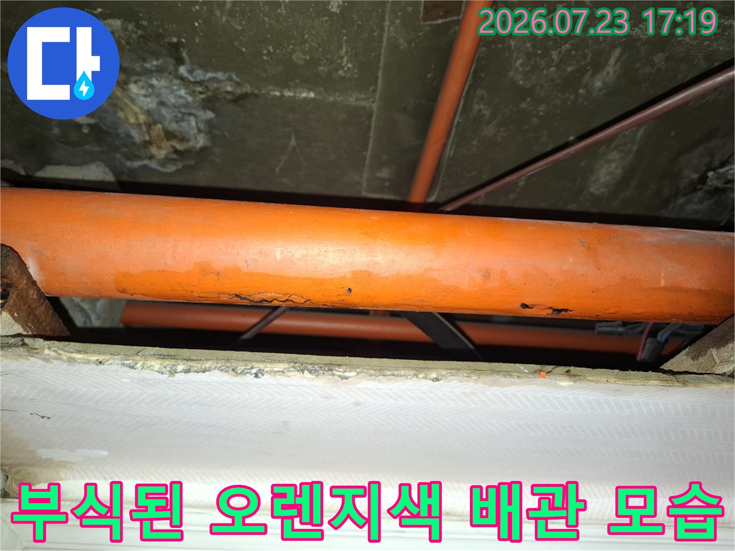 천장 내부에 설치된 부식이 진행되어 표면이 거칠어진 오렌지색 배관-사진