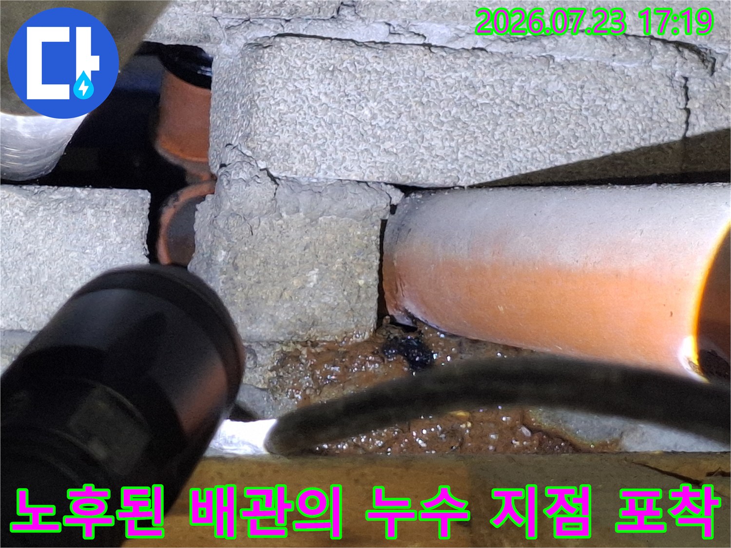 회색 벽면 아래 설치된 오렌지색 배관-외벽 부식 및 누수 현상