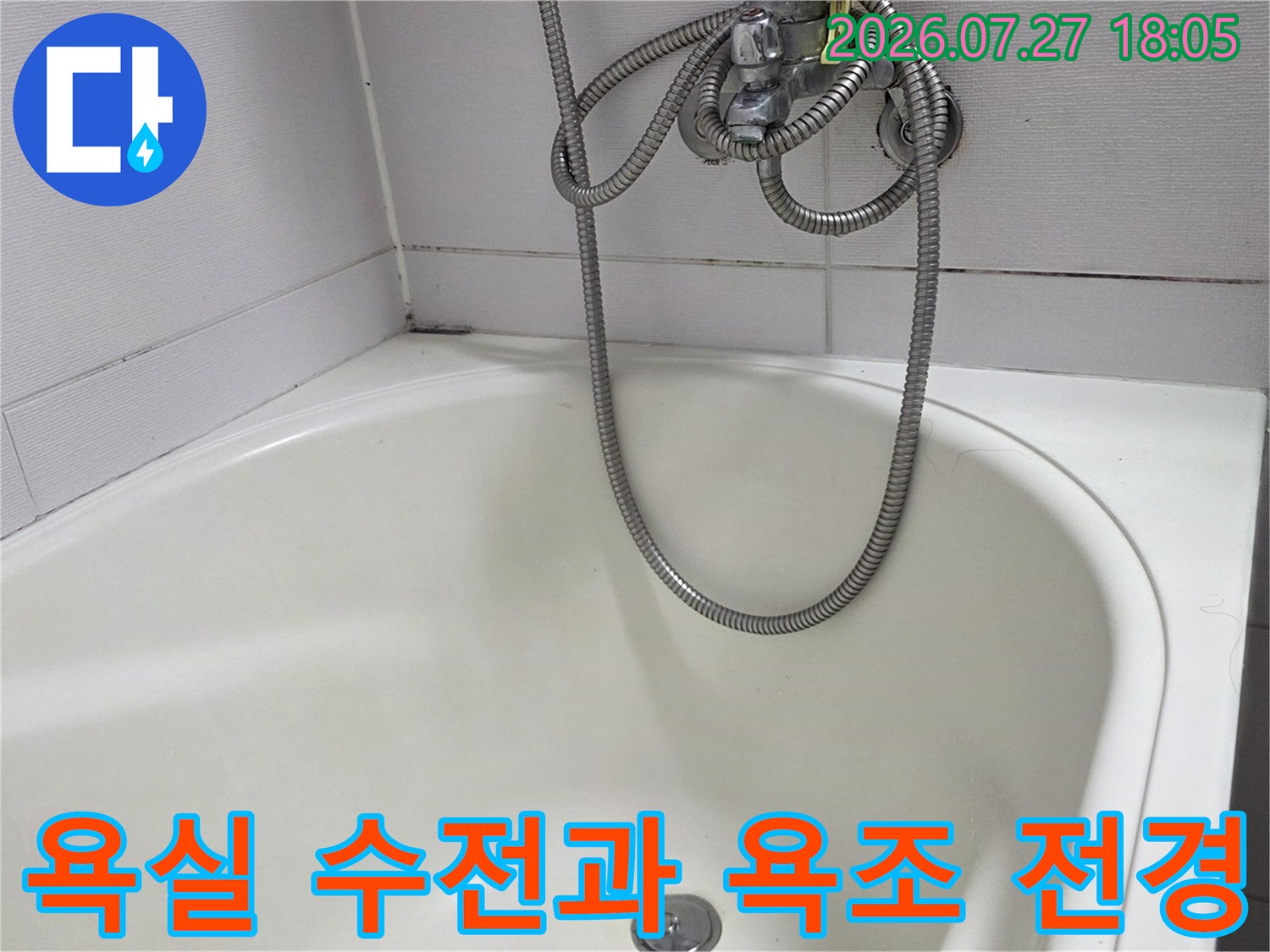 벽면 타일에 설치된 샤워 수전에서 내려오는 호스가 흰색 욕조에 닿아 있는 사진