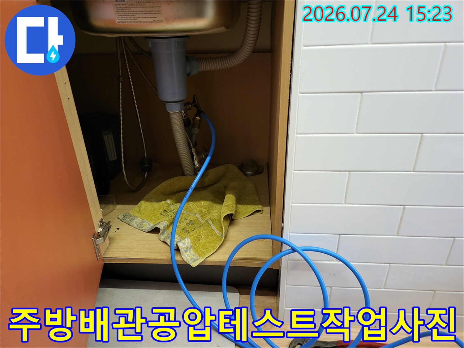 싱크대 하단 배관 연결 부위에 파란색 호스와 장비가 설치된 현장 사진