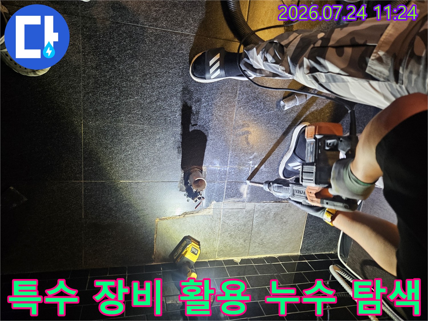강력한 조명 아래 전문 청음 장비를 사용하여 배관 누수 위치를 찾는 장면