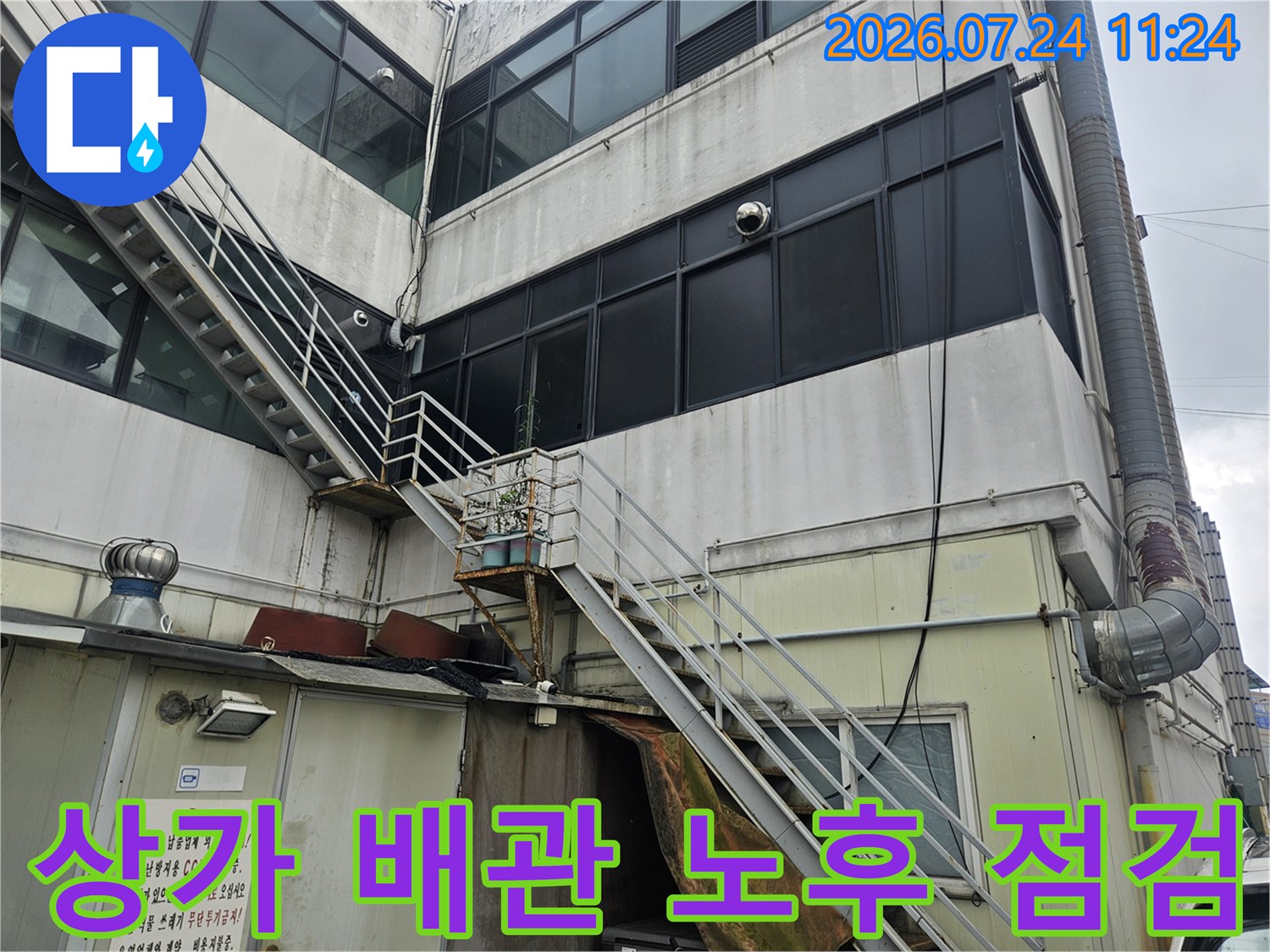 상가 건물 외벽과 연결된 노후된 배관 및 구조물 전경
