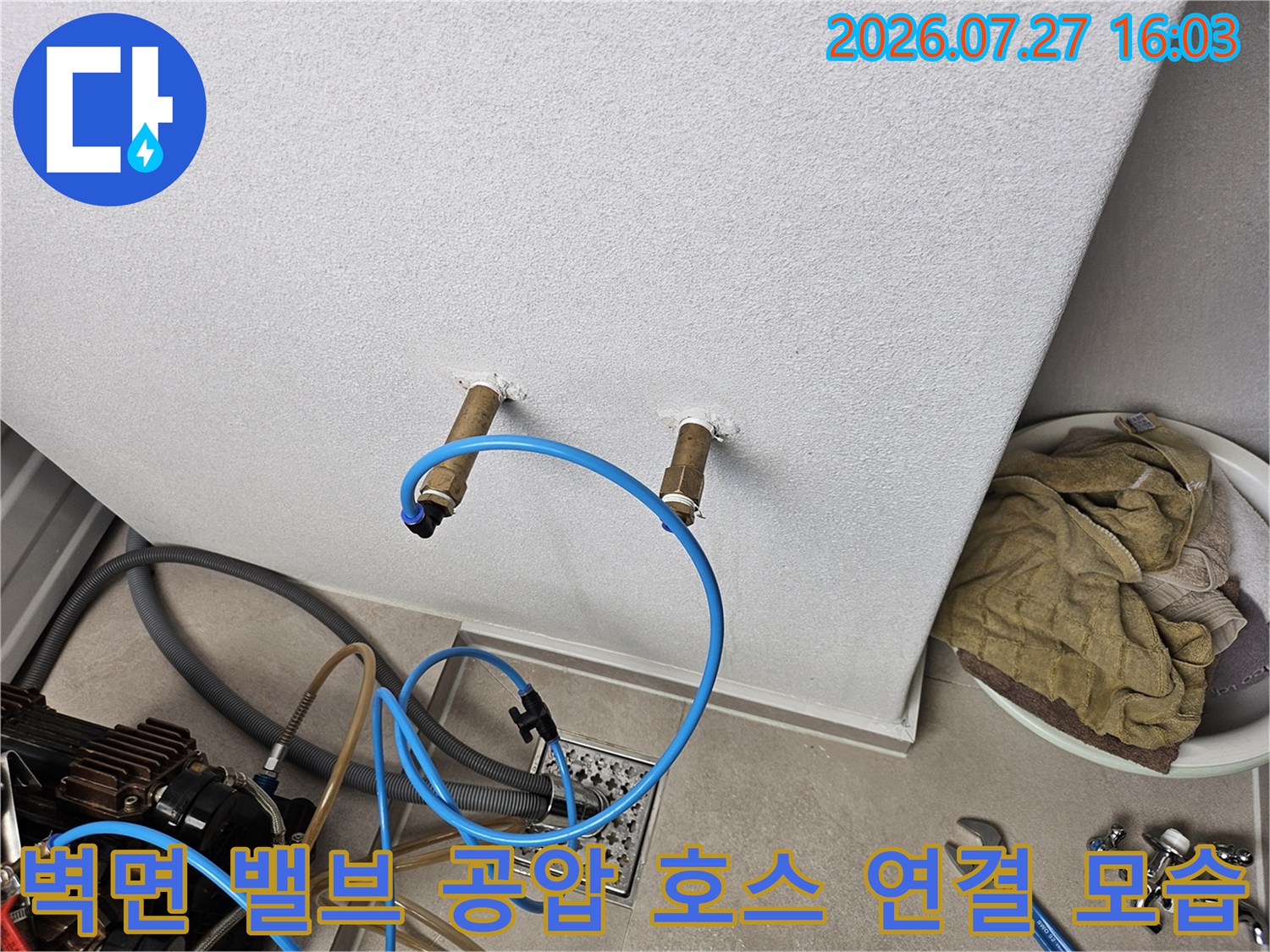 흰색 벽면에 돌출된 두 개의 배관 끝단에 파란색 고무 호스가 연결되어 측정 중인 사진