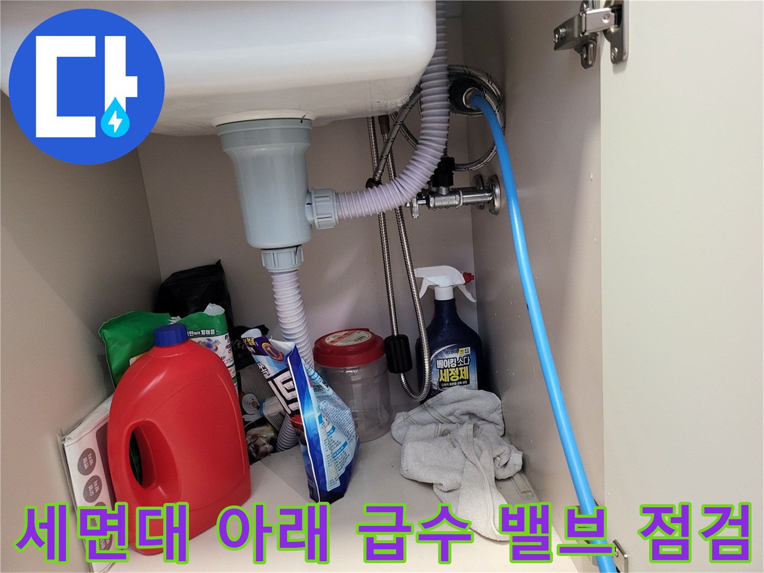 세면대 하부의 금속 배관과 자바라 호스 및 주변 물품들입니다.
