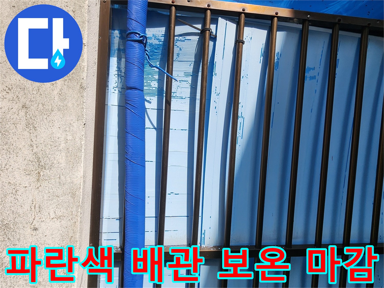 금속 격자 구조물 아래에 설치된 파란색 보온재 씌워진 배관입니다.
