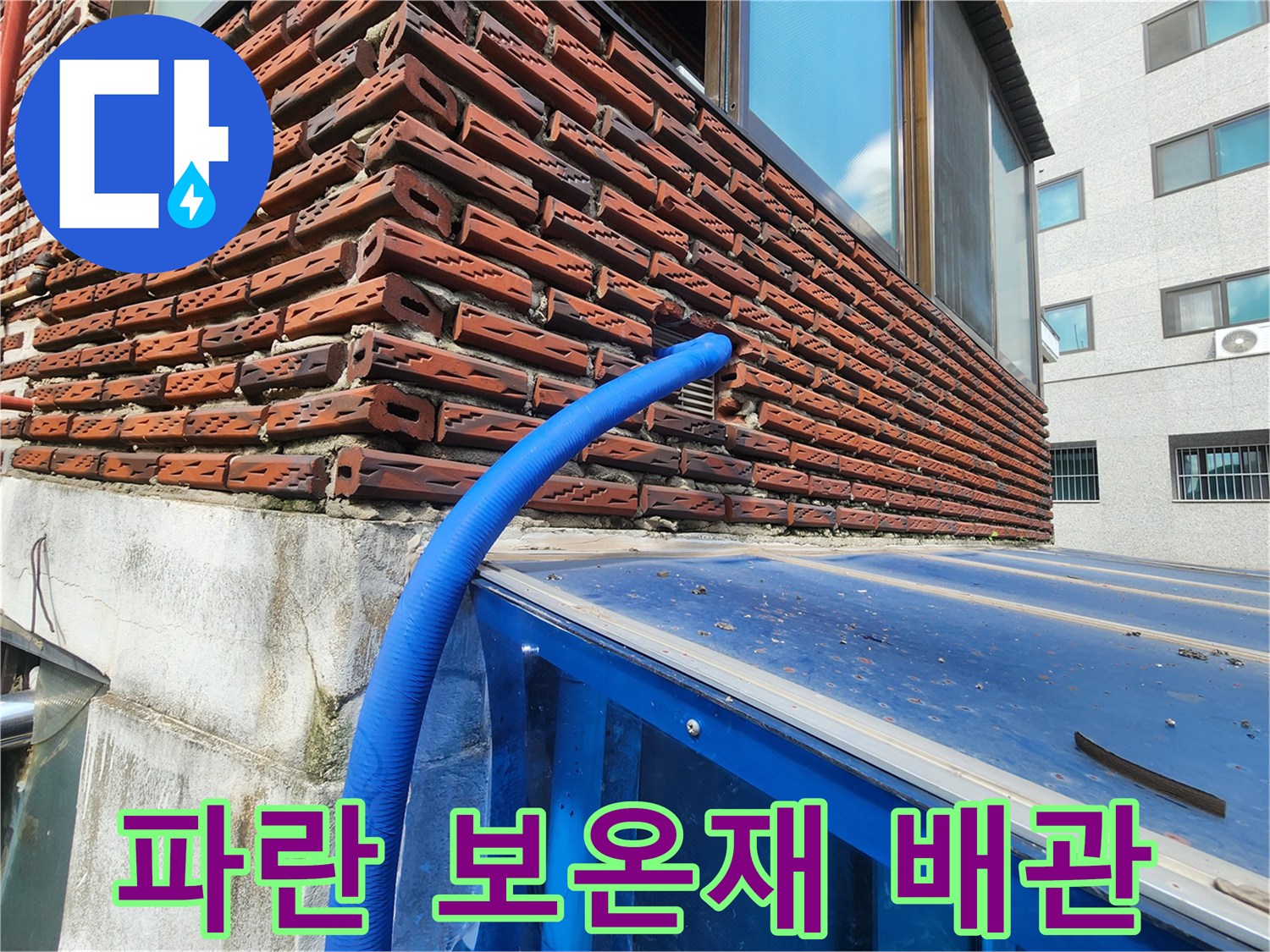 붉은 벽돌 외벽에 설치되어 외부로 노출된 파란색 배관 구조