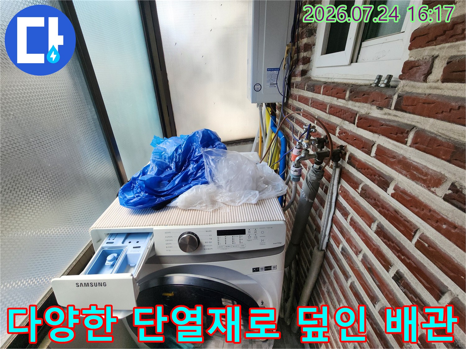 세탁기 위쪽을 지나는 파란색 보온제와 은색 단열재가 입혀진 수도라인