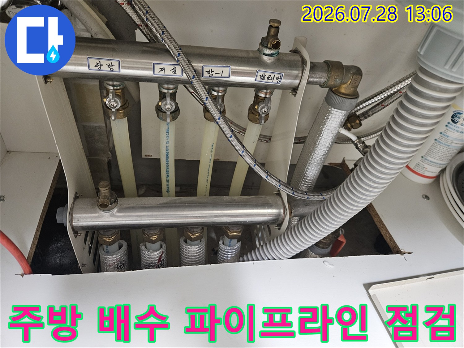 다양한 각도의 배출관과 연결부가 노출된 싱크대 하부 공간의 상세 모습