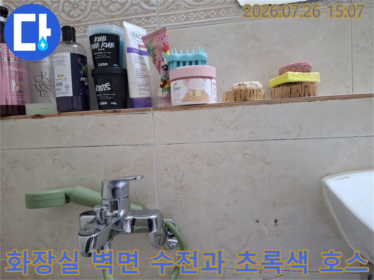 욕실 선반 아래에 위치한 금속 재질의 수도꼭지와 배관 연결 상태