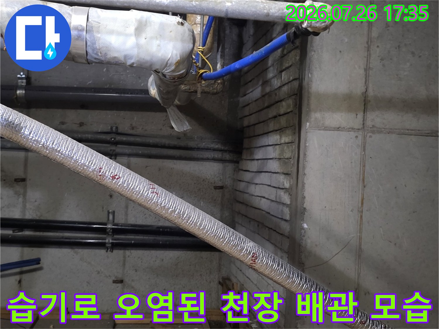 콘크리트 천장에 고정된 파란색 배관과 은색 보온재 배관 주변의 누수 흔적 사진