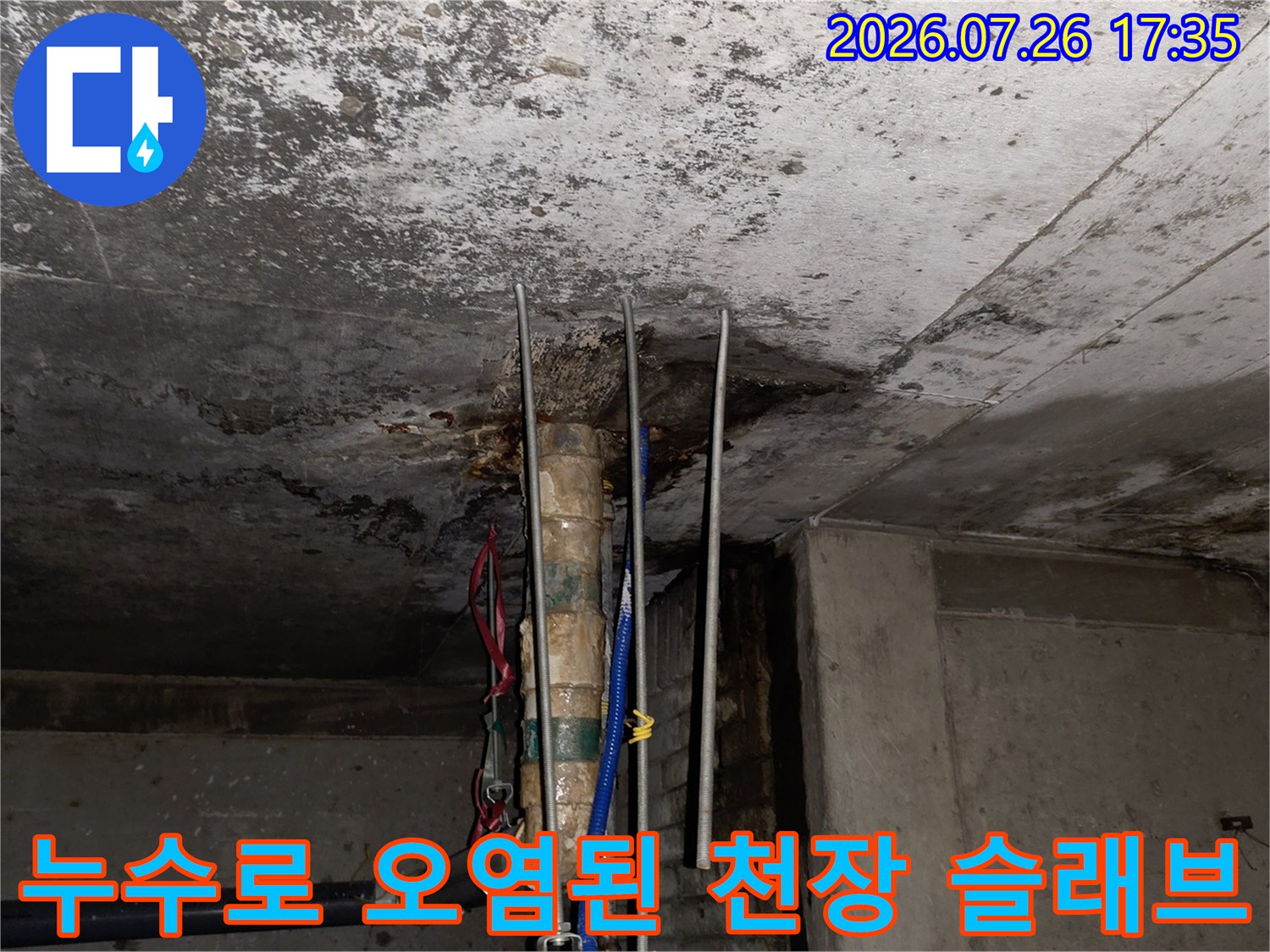 콘크리트 천장에 발생한 짙은 누수 얼룩-파란색과 빨간색 배관이 설치된 모습