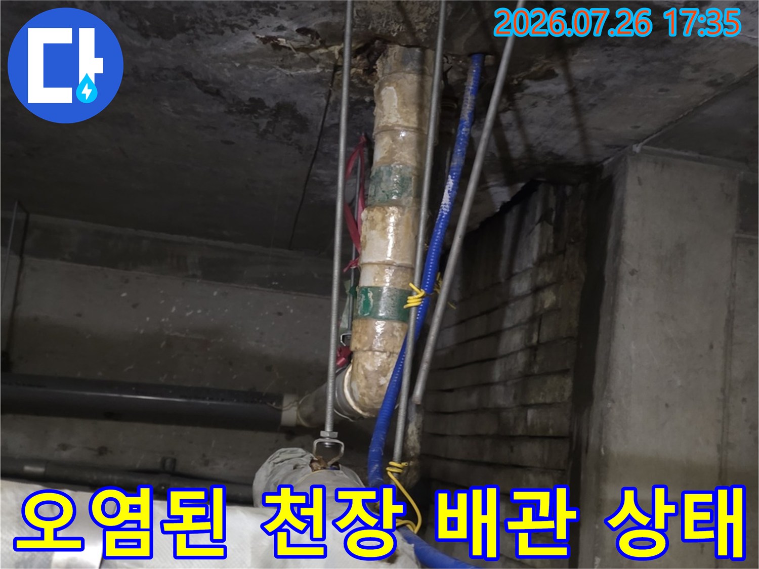 콘크리트 천장에 설치된 오염된 배관과 파란색 호스가 지나가는 모습
