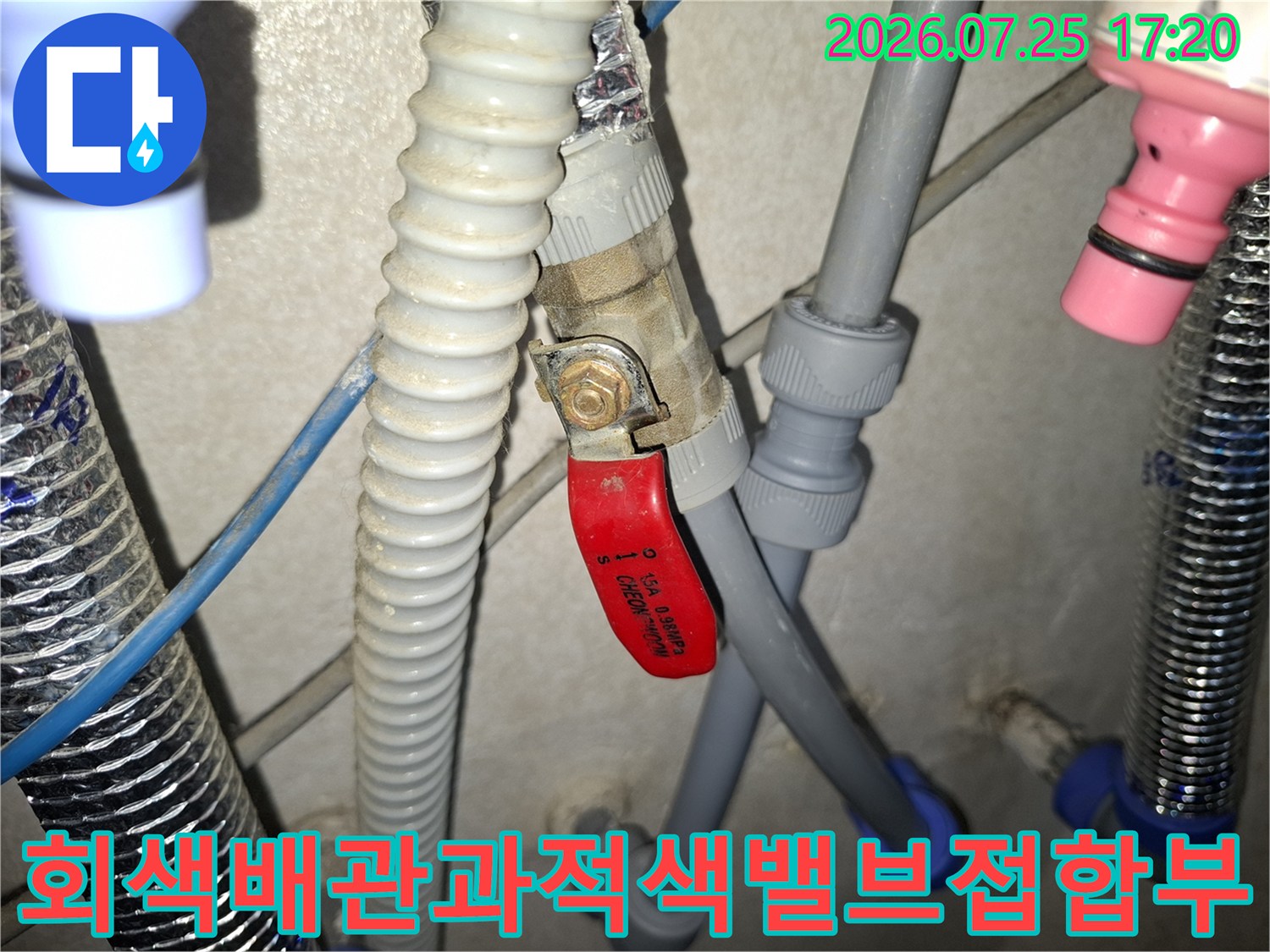 은색 보온재와 회색 배관 그리고 적색 밸브 핸들이 연결된 설비 구조