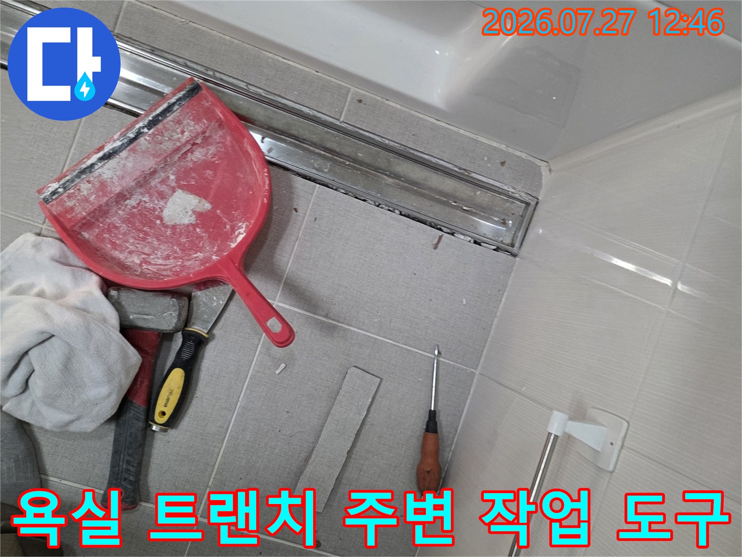 욕실 바닥-트랜치 배수구 주변에 배치된 빨간색 헤라와 드라이버-칼 등 보수 장비들