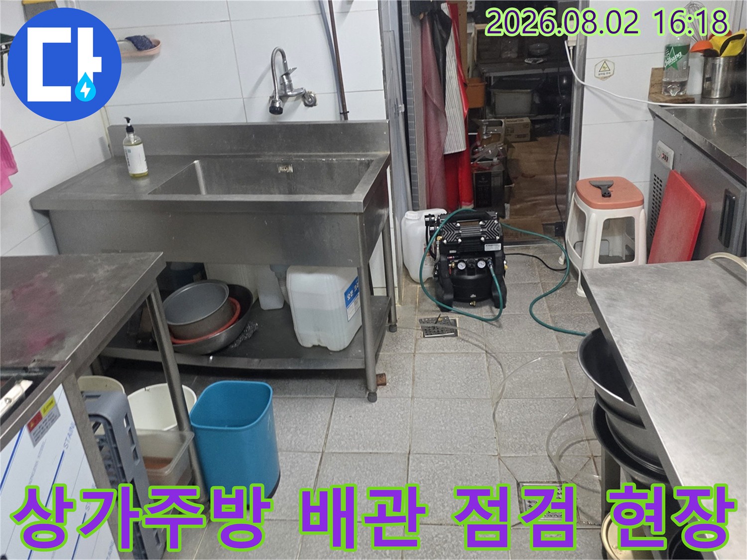 상업용 주방 싱크대 하단 배관의 누수 여부를 확인하기 위해 공압 테스트 장비를 연결하여 점검하는 모습