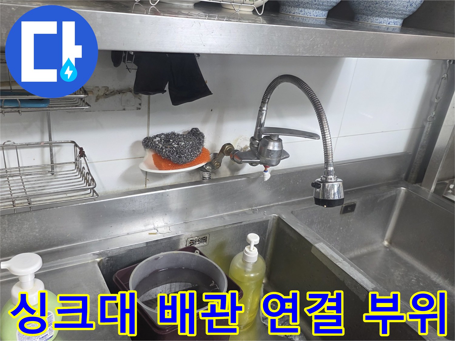 스테인리스 싱크대 아래쪽의 수도 배관과 벽면 타일