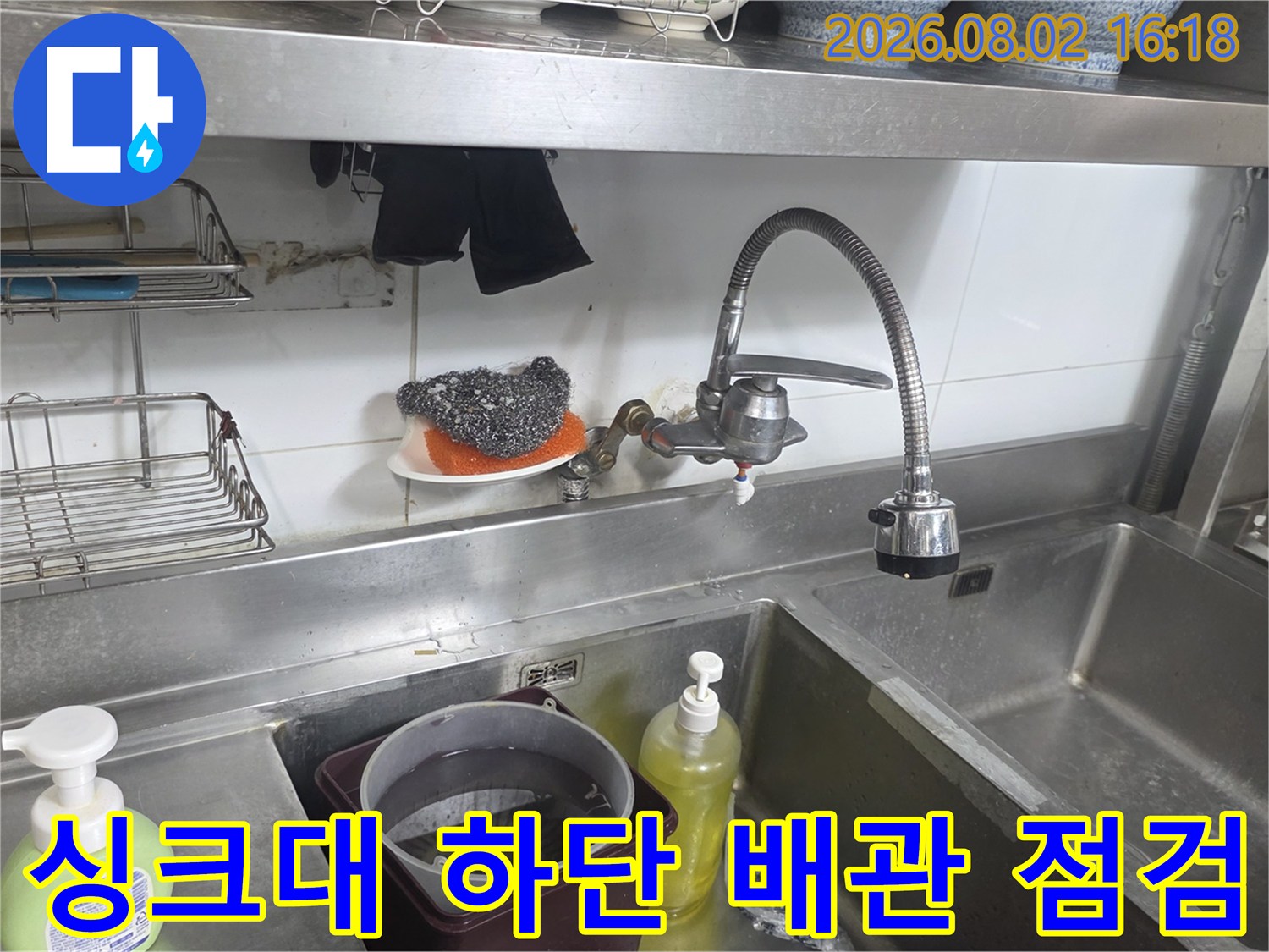 싱크대 아래쪽 수도 배관과 수전이 설치된 모습