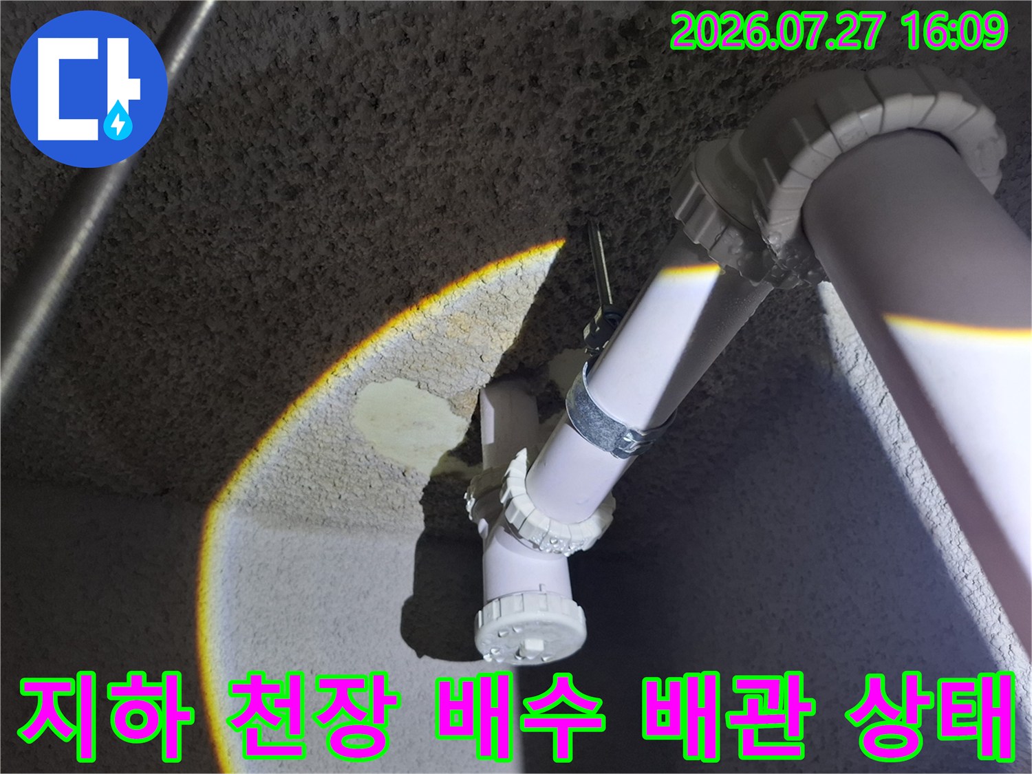 콘크리트 천장에 설치된 흰색 플라스틱 배수 배관-연결 부위 점검 모습
